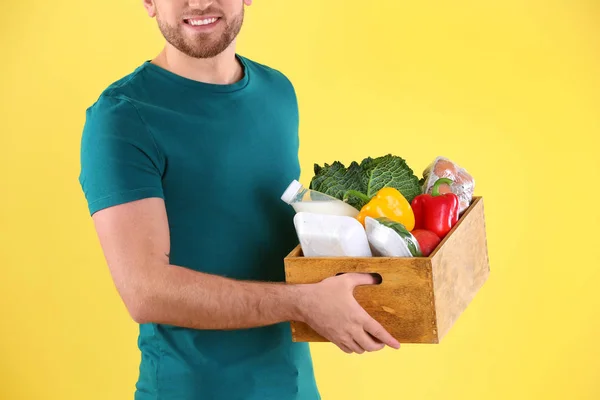 Lieferant Hält Holzkiste Mit Lebensmitteln Auf Farbigem Hintergrund — Stockfoto