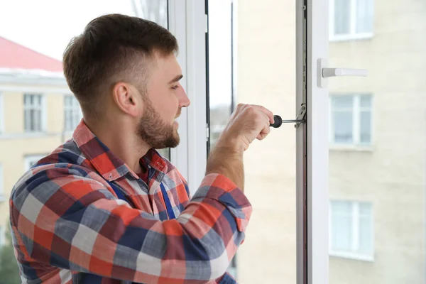 Construction worker adjusting installed window with screwdriver indoors