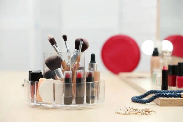 Organizer with cosmetic products and makeup accessories on dressing table