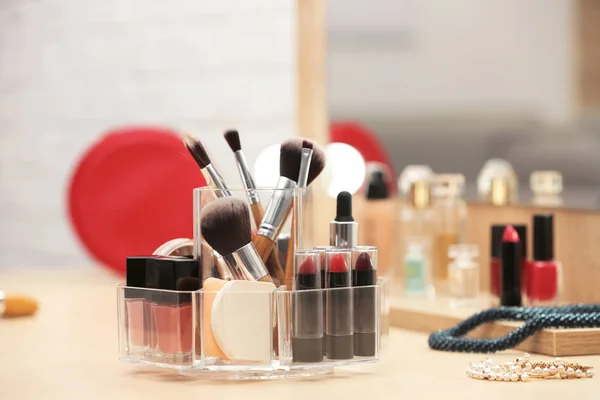 Organizer with cosmetic products and makeup accessories on dressing table