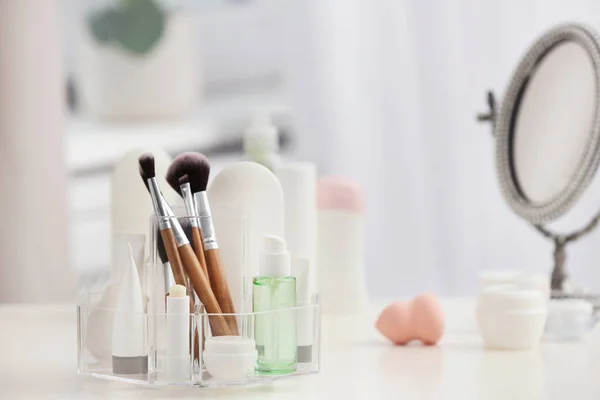 Organizer with cosmetic products and makeup accessories on table against blurred background. Space for text