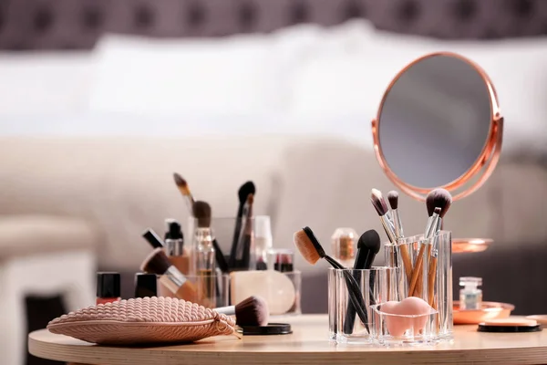 Makeup accessories and cosmetic products on table against blurred background. Space for text