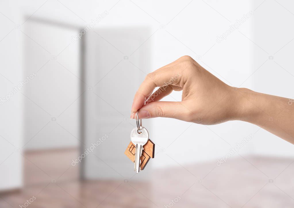 Woman holding house key in modern apartment, closeup