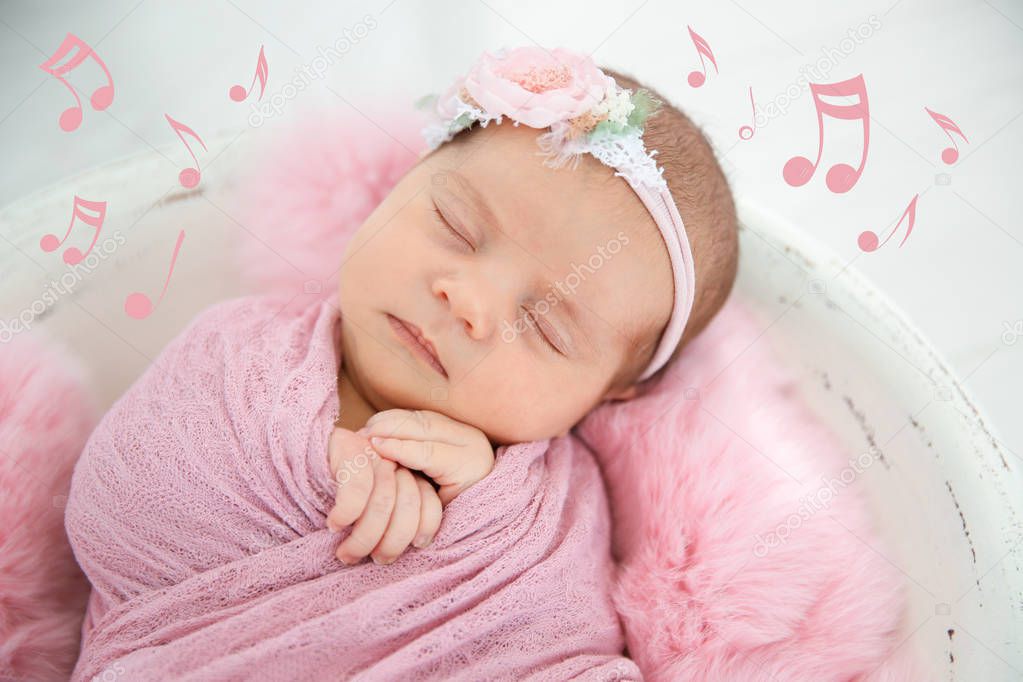 Cute newborn girl lying in baby nest and flying music notes, closeup. Lullaby song