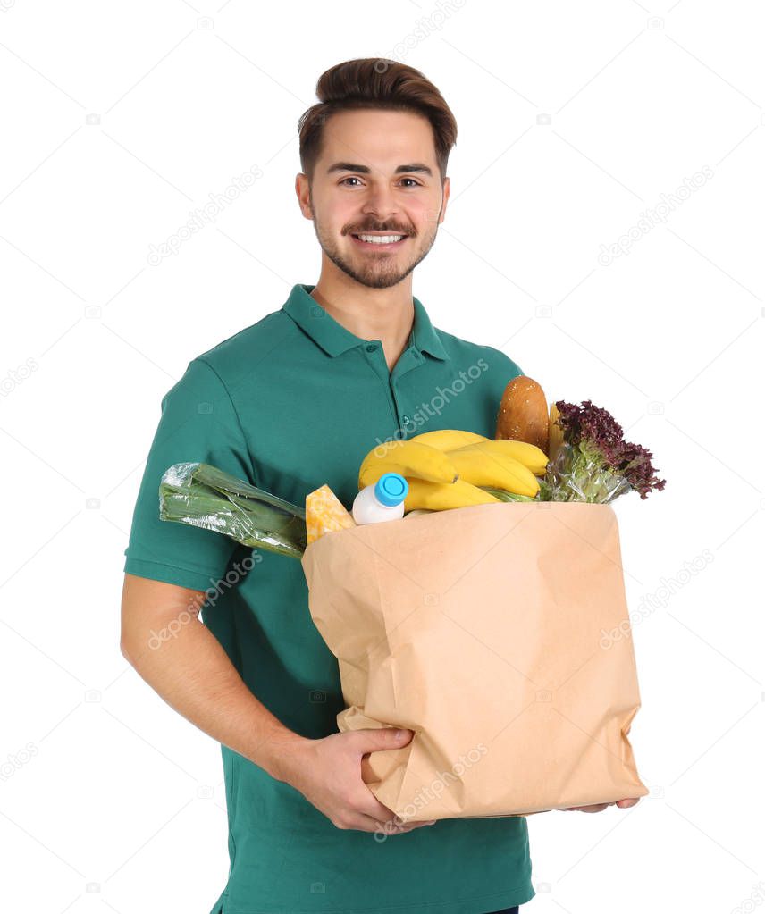 Young man holding paper bag with products on white background. Food delivery service