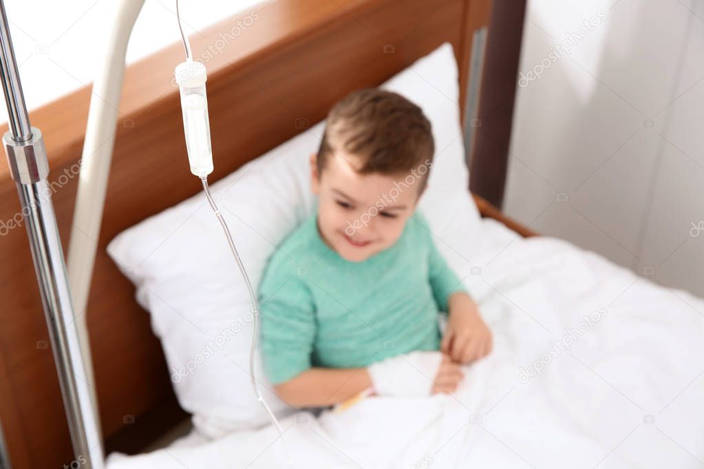 Little child with intravenous infusion in hospital bed, focus on drip chamber