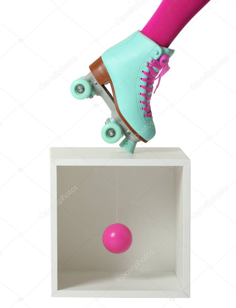 Woman wearing vintage roller skate and storage cube with ball on white background, closeup