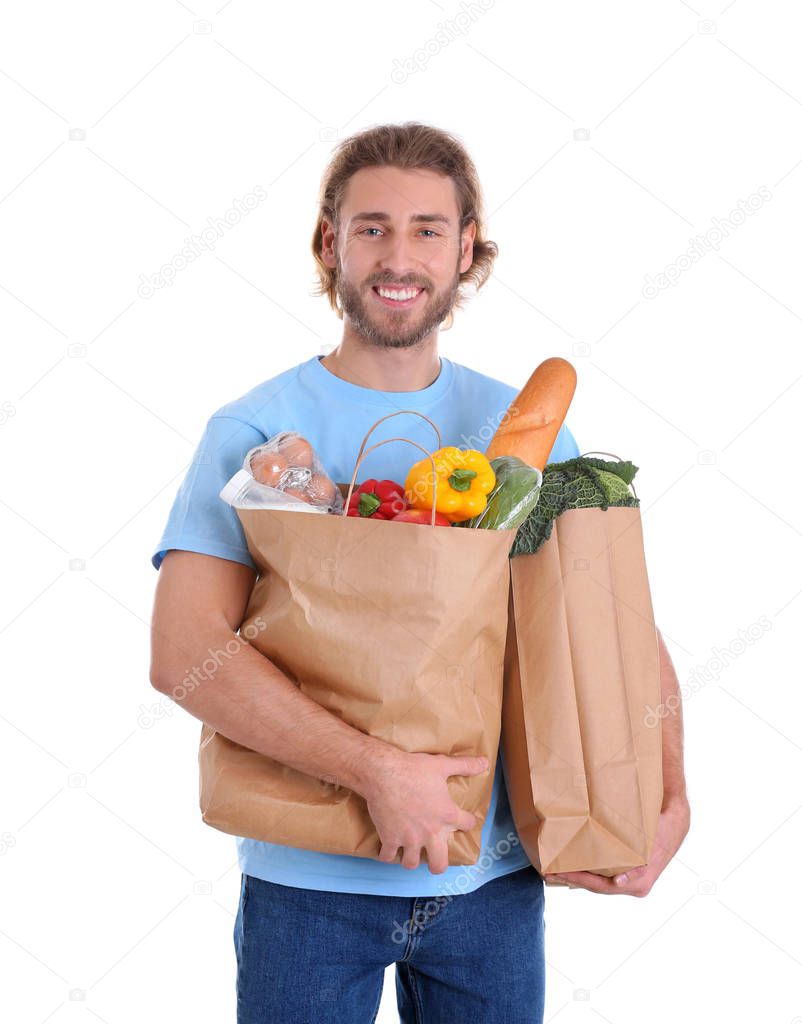 Delivery man holding paper bags with food products on white background