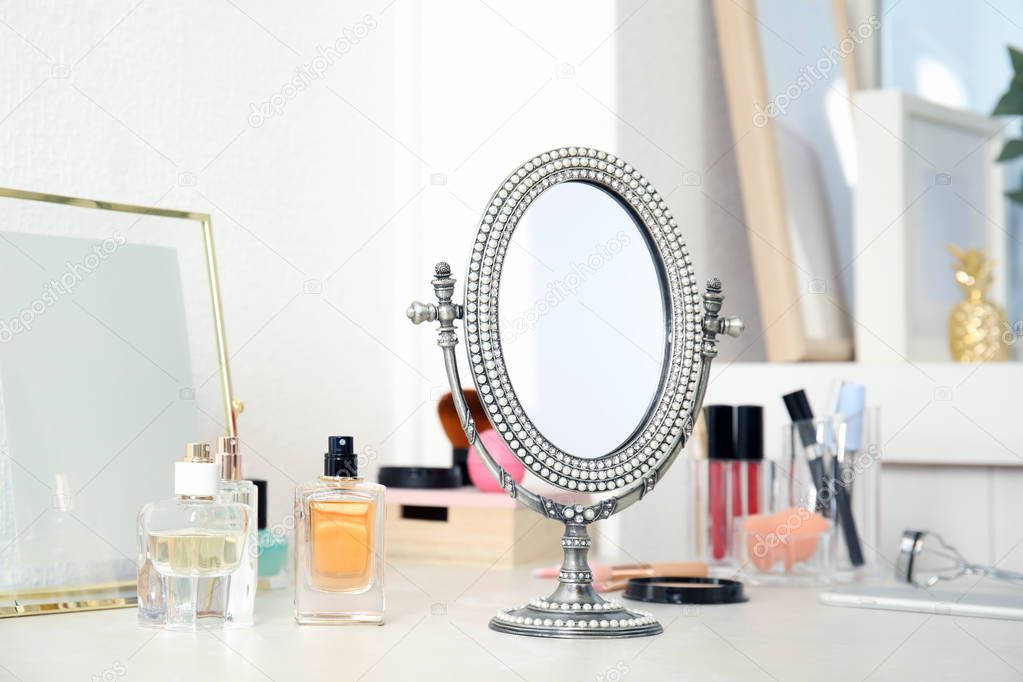 Mirror in antique frame and different cosmetics on dressing table. Beauty blogger