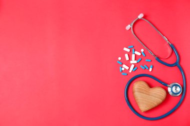 Stetoskop, hap ve kalp üzerinde renk arka plan, metin için yer düz yatıyordu kompozisyonu. Kardiyoloji kavramı
