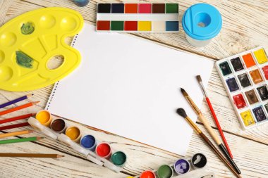 Farklı boyalar, fırçalar ve kağıt ahşap arka plan üzerinde düz yatıyordu kompozisyonu. Metin için yer