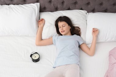 Çalar saat görünümünün üst yatakta uyuyan güzel küçük kız