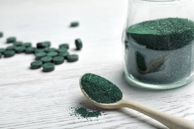 Kaşık ve spirulina tozu ahşap zemin üzerine kavanoz. Metin için yer