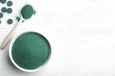 Spirulina tozu ve boşluk veya beyaz ahşap arka plan üzerinde metin ile düz yatıyordu kompozisyon