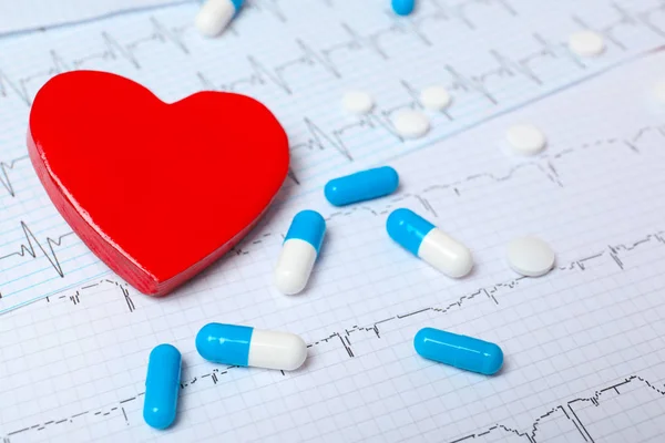 Red heart with pills on cardiogram. Cardiology concept