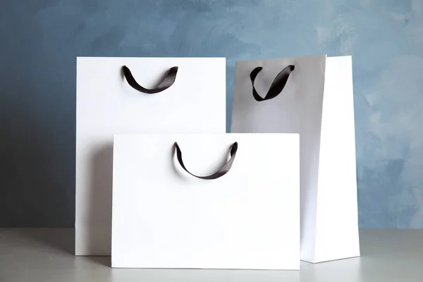 Paper shopping bags on table against color background. Mock up for design