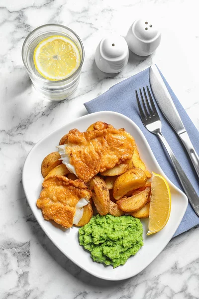 Plate with British traditional fish and potato chips on marble background, top view