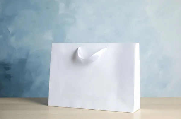 Paper shopping bag on table against color background. Mock up for design