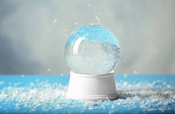 Magical empty snow globe on table against light background