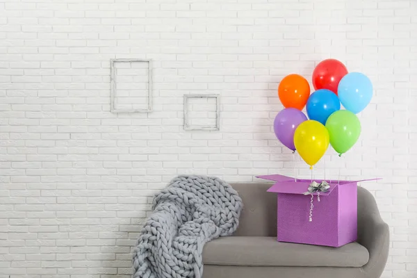 Geschenkbox Mit Hellen Luftballons Auf Sofa Vor Weißer Ziegelwand Raum — Stockfoto