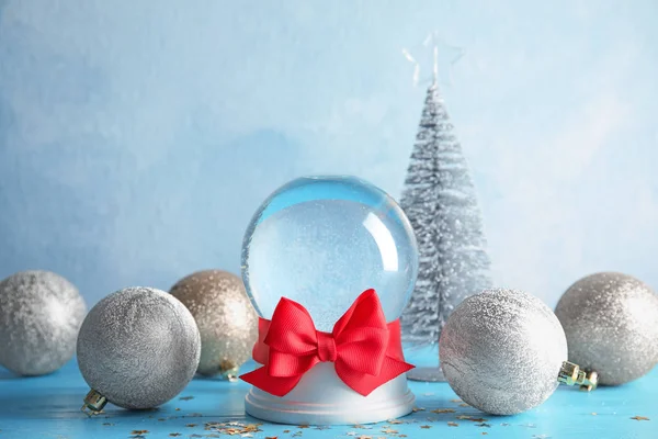 Empty snow globe with red bow and Christmas decorations on table