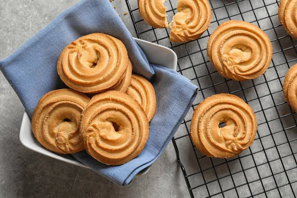 Bowl and baking rack with Danish butter cookies on grey table, top view