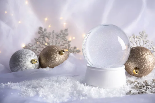 Magical empty snow globe with Christmas decorations on white fabric. Space for text