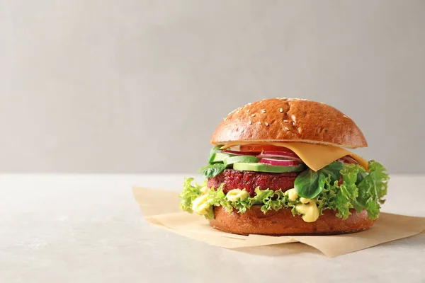 Tasty vegetarian burger with beet cutlet on table against light background. Space for text