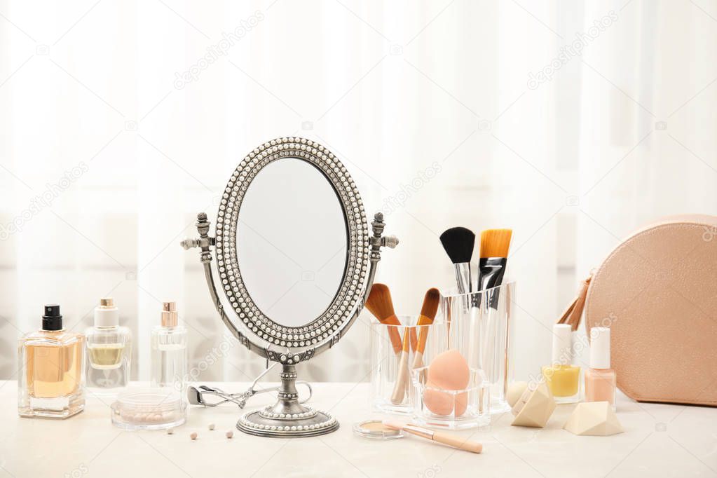 Mirror in antique frame and different cosmetics on dressing table. Beauty blogger