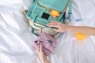 Kadın yatakta, üstten görünüm annelik sırt çantası içine bebek aksesuarları ambalaj