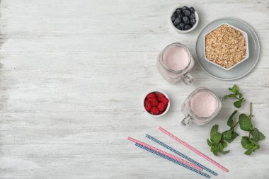 Kompozisyon sağlıklı protein shake ile mason kavanoz, malzemeler ve beyaz ahşap zemin üzerinde metin için yer düz yatıyordu