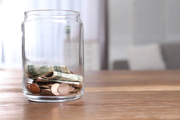 Donation jar with money on table against blurred background. Space for text
