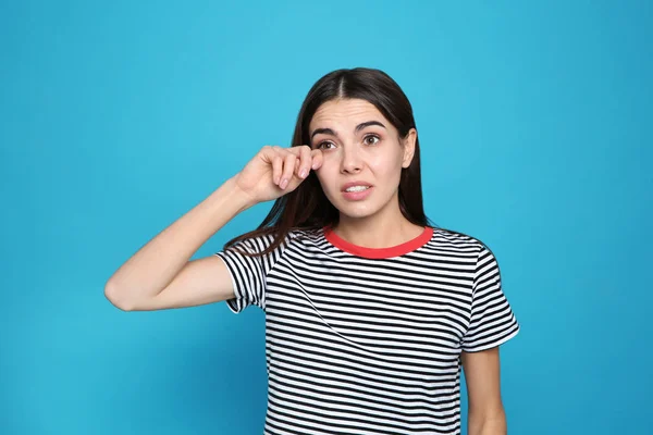 Young woman rubbing eye on color background. Annoying itch