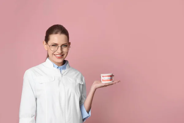 Female dentist holding jaws model on color background. Space for text