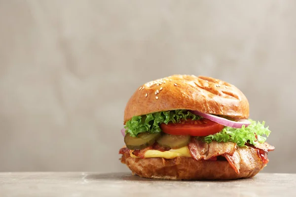 Delicious burger with bacon on table against grey background. Space for text