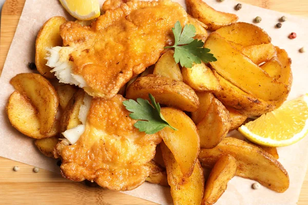 British traditional fish and potato chips on wooden background, closeup