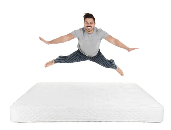 Junger Mann Springt Auf Matratze Vor Weißem Hintergrund — Stockfoto
