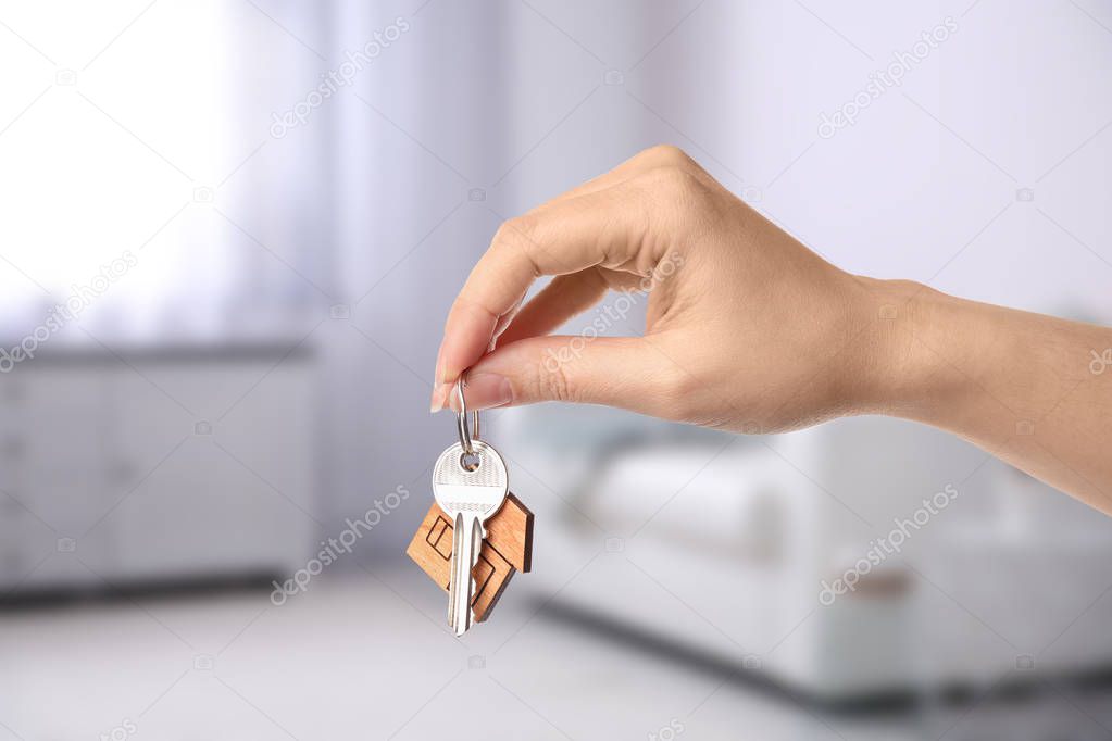 Woman holding house key in modern living room, closeup