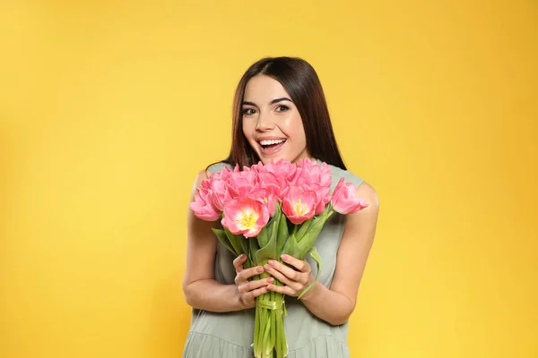 春チューリップ黄色の背景で美しい笑みを浮かべて少女の肖像画 国際女性の日 — ストック写真