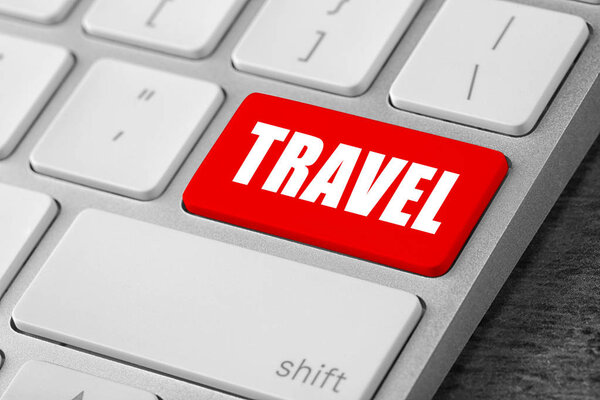 Computer keyboard with red button and word Travel. Tourist agency