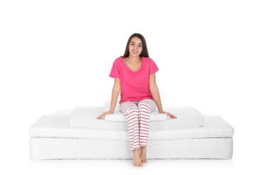 Yatak kazık beyaz arka plan üzerinde oturan genç kadın