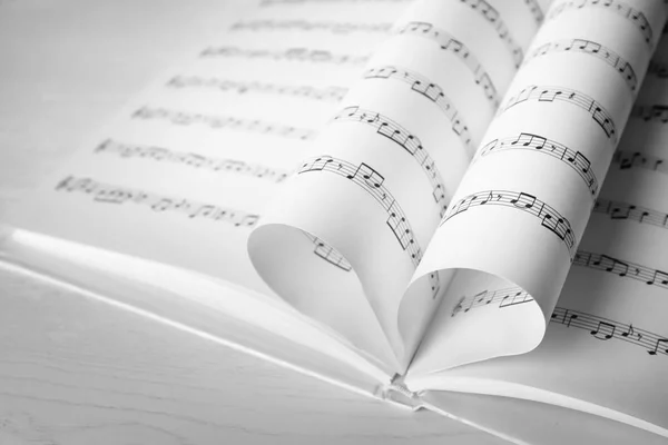 stock image Heart made of book pages with music notes on table, closeup. Space for text