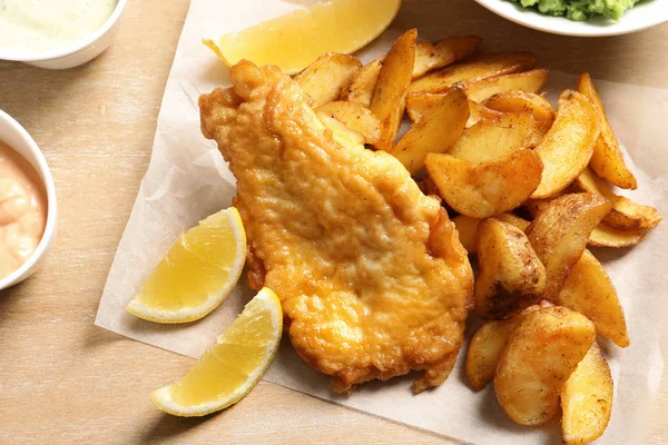 British traditional fish and potato chips on wooden background, closeup