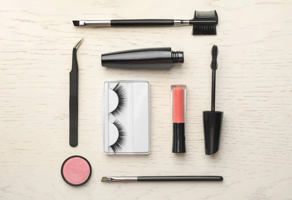 Flat lay composition with artificial eyelashes and accessories on wooden background