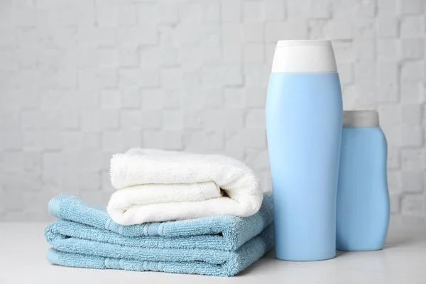 Gefaltete Handtücher Und Shampoo Auf Dem Tisch Vor Weißer Wand — Stockfoto
