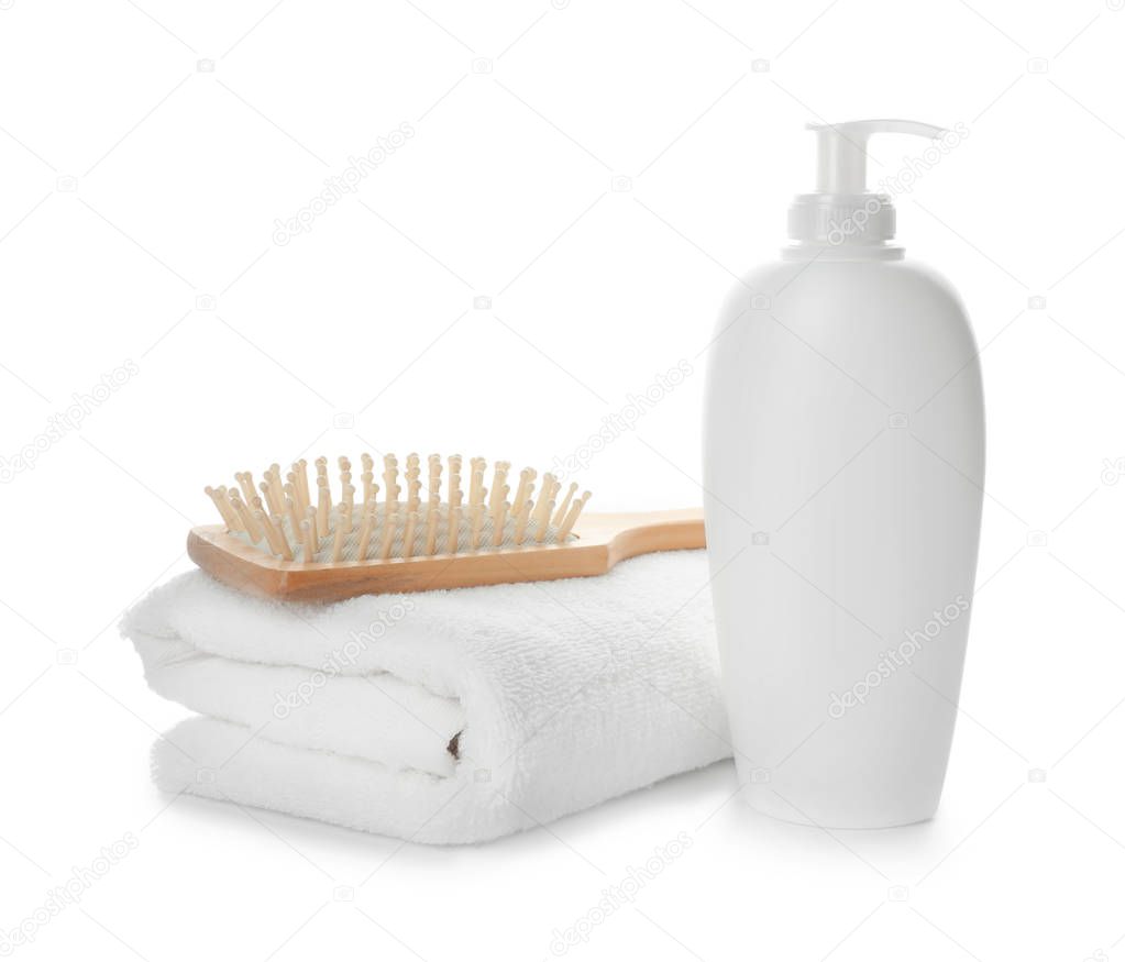 Folded towel, hair brush and shampoo isolated on white