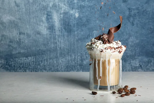 おいしいコーヒーにホイップ クリームとチョコレート色の背景にテーブルの上のガラスのコップ テキストのためのスペース — ストック写真