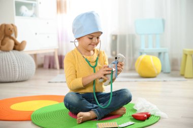Şirin çocuk kendini doktor olarak stetoskop ve oyuncak ayı ile evde oynarken hayal