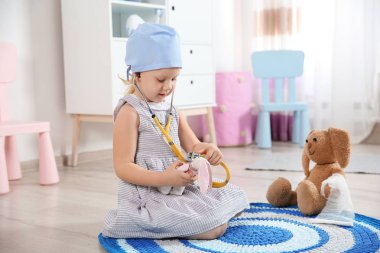 Şirin çocuk kendini doktor olarak stetoskop ve oyuncak tavşan ile evde oynarken hayal