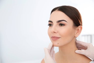 Klinikte genç hastanın doğum lekesi inceleyerek dermatolog. Metin için yer